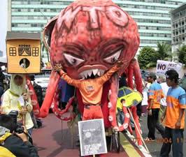 picture of protester, one is putting his head inside a paper-mache octopus that represents the W T O
