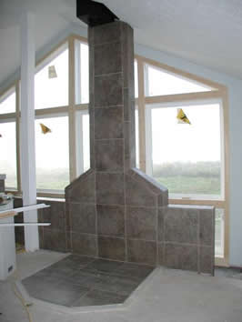picture of hearth wall made of block and tile, positioned in front of large window array