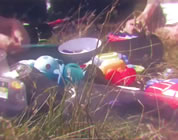 plastic pollution video link; thumb of assorted plastic items on a picnic blanket